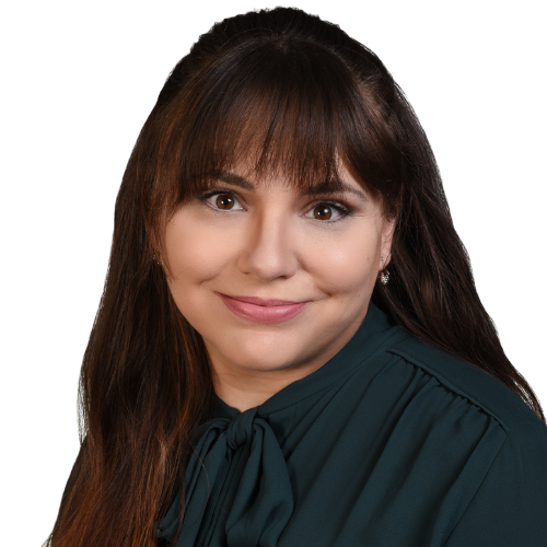 Head-and-shoulders portrait of a smiling woman with long brown hair and a dark green blouse, looking at the camera.